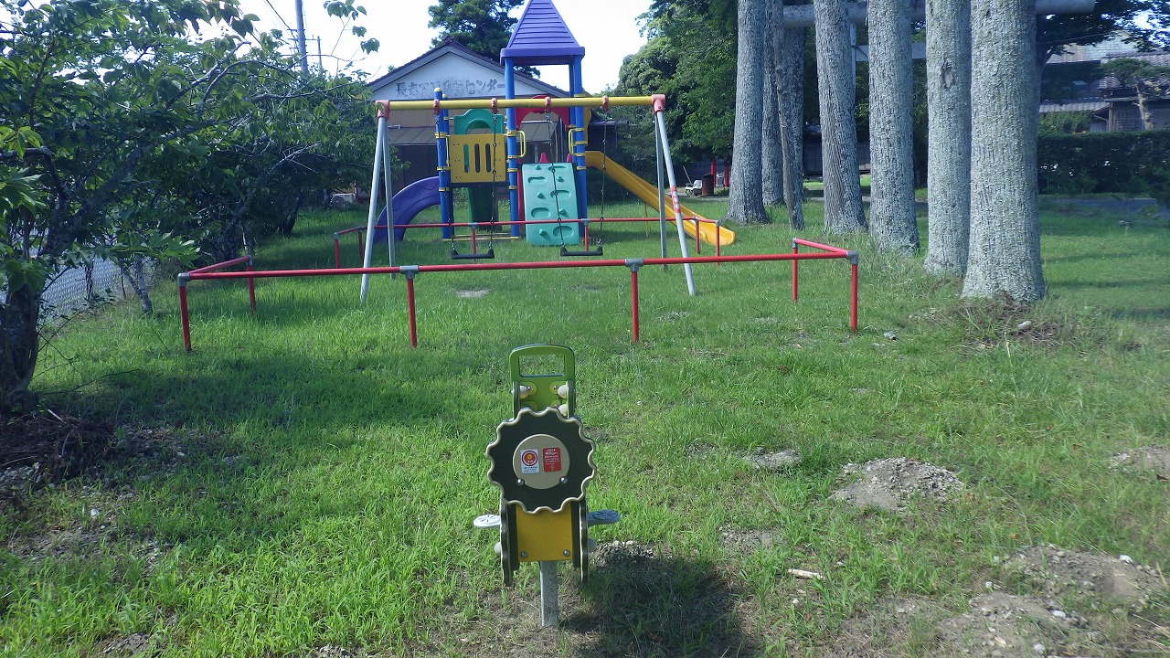 長志児童遊園の全体写真。奥にすべり台、手間にブランコ、スプリング遊具が写っています。