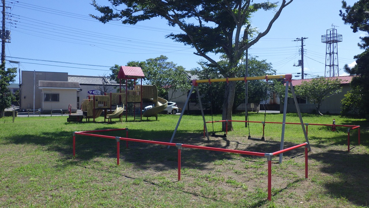 渋田児童遊園の芝の上にブランコが1基・複合遊具が1基写っています。