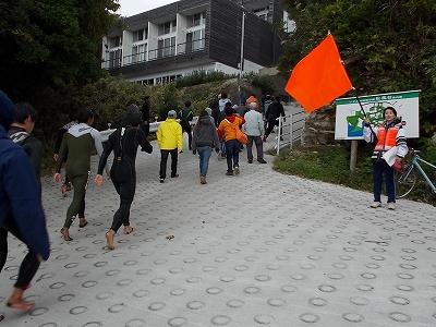 赤い旗を振っている人が大勢の観光客を避難経路へ誘導している避難訓練の様子を撮影した写真
