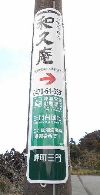 別荘和久庵の場所の方向を示す赤の右矢印と電話が掲載された下に、津波緊急避難場所の案内表示がある広告が電柱に掲出された写真
