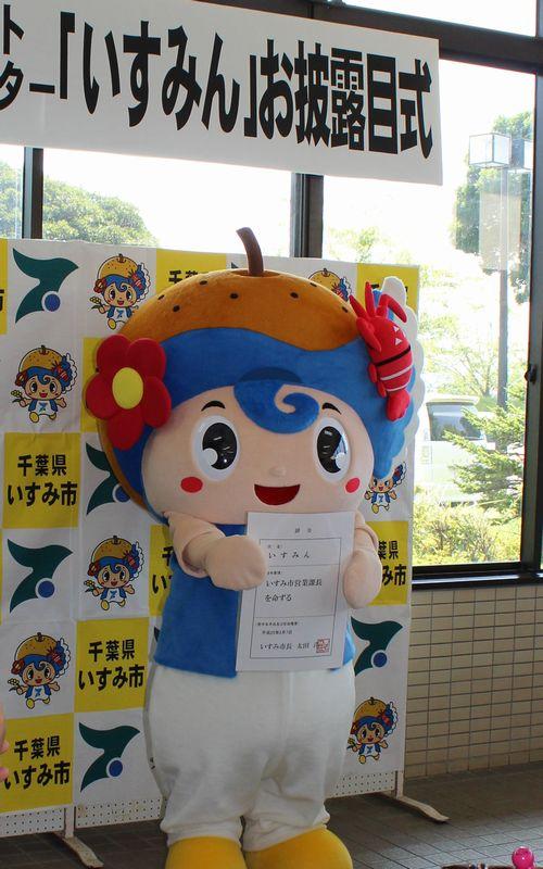 お披露目式で、千葉県いすみ市と書かれたボードを背に、いすみ市営業課長の辞令を持つ、いすみ市のキャラクター「いすみん」の写真