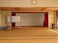 畳張りの大きな部屋に、ステージがあり、大きな水色のボードも完備されている和室の写真